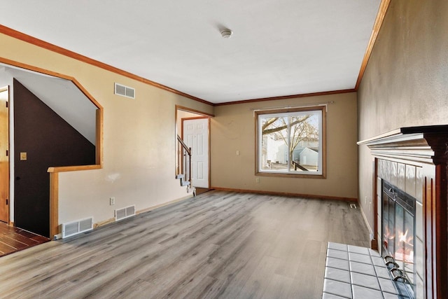 unfurnished living room with a tiled fireplace, visible vents, and wood finished floors