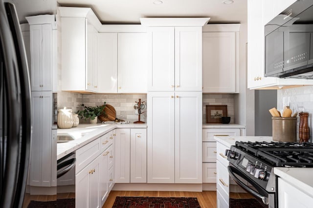 kitchen featuring white cabinets, decorative backsplash, and black appliances