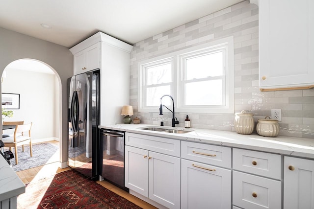 kitchen featuring white cabinetry, sink, dishwashing machine, decorative backsplash, and black refrigerator with ice dispenser