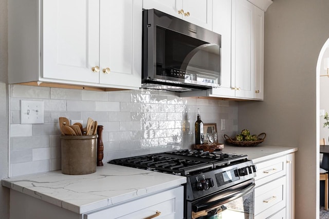 kitchen featuring stainless steel appliances, tasteful backsplash, light stone countertops, and white cabinets