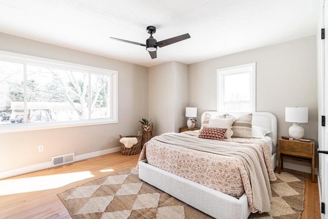 bedroom with ceiling fan, light hardwood / wood-style floors, and multiple windows