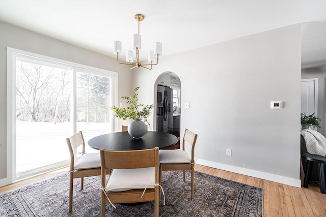 dining space with hardwood / wood-style floors and a notable chandelier