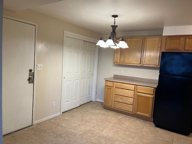 kitchen featuring black fridge, an inviting chandelier, and hanging light fixtures