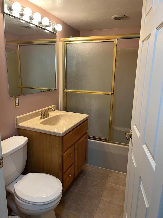 full bathroom with shower / bath combination with glass door, tile patterned floors, vanity, and toilet