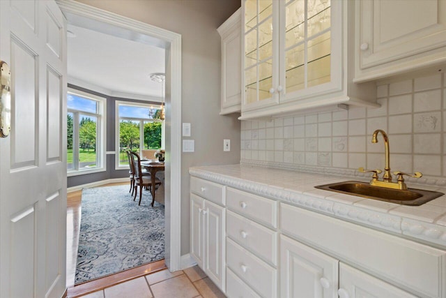 N84W36411 Riverwood Ln, Oconomowoc, WI 53066 - kitchen featuring white cabinets, decorative backsplash, sink, and light tile patterned floors