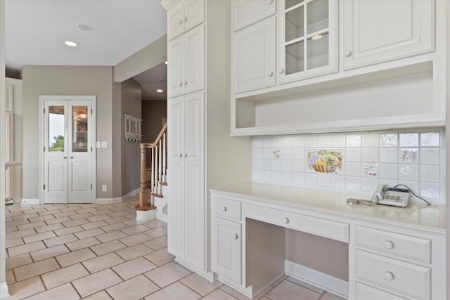 N84W36411 Riverwood Ln, Oconomowoc, WI 53066 - kitchen featuring light tile patterned floors, decorative backsplash, built in desk, and white cabinets