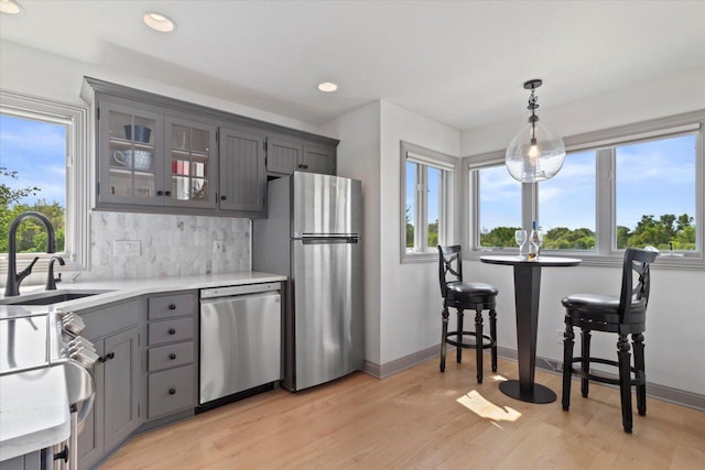 N84W36411 Riverwood Ln, Oconomowoc, WI 53066 - kitchen featuring gray cabinets, stainless steel appliances, backsplash, pendant lighting, and sink