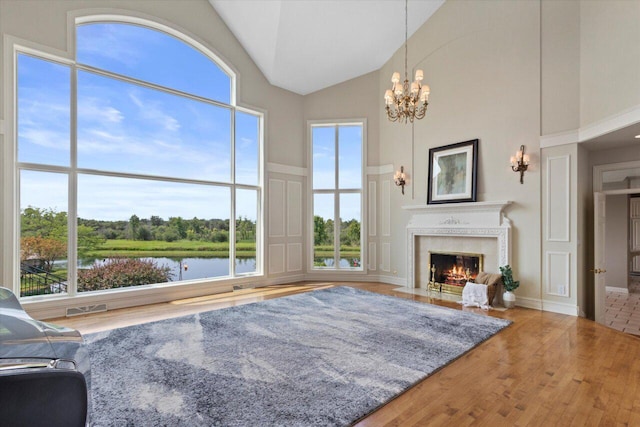N84W36411 Riverwood Ln, Oconomowoc, WI 53066 - living room featuring a chandelier, a water view, wood-type flooring, and high vaulted ceiling