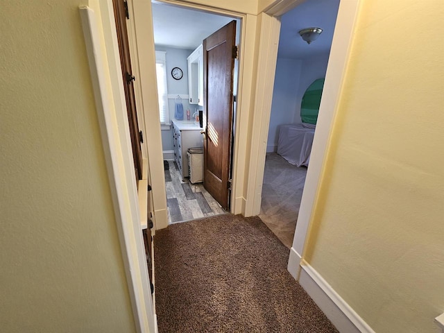 hallway with carpet floors and baseboards