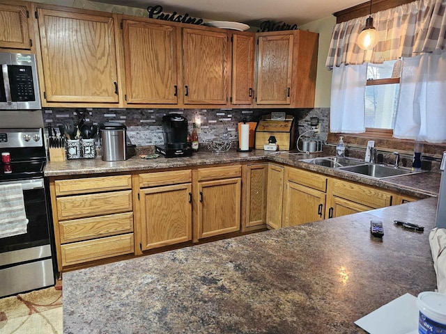 kitchen featuring appliances with stainless steel finishes, dark countertops, a sink, and decorative backsplash