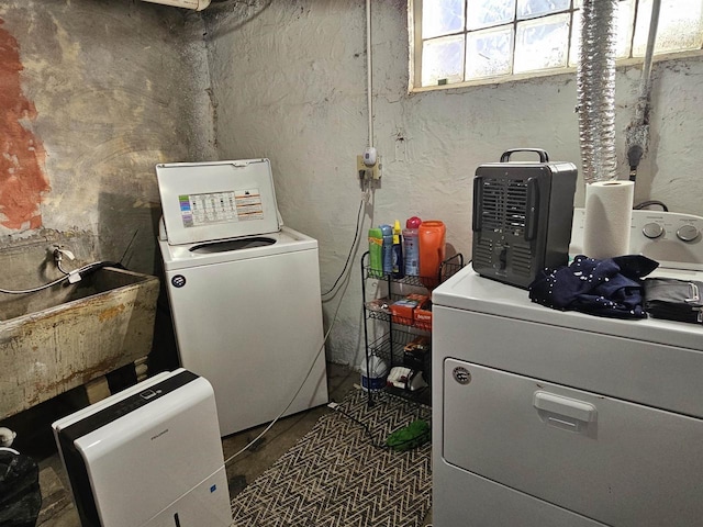 clothes washing area featuring laundry area, separate washer and dryer, and a sink