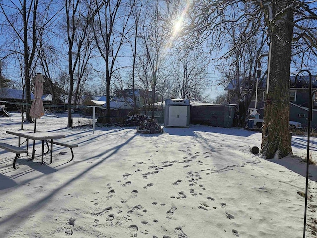 yard covered in snow with fence and an outdoor structure