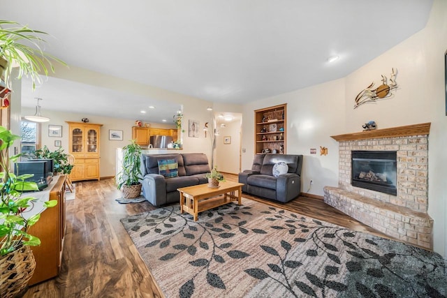 living room featuring a fireplace, built in features, and hardwood / wood-style floors