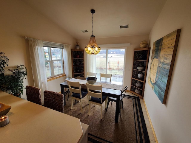 dining area with lofted ceiling, tile patterned flooring, and an inviting chandelier