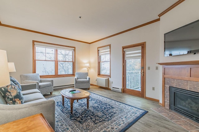 living room featuring a baseboard heating unit, ornamental molding, wood-type flooring, and a tile fireplace