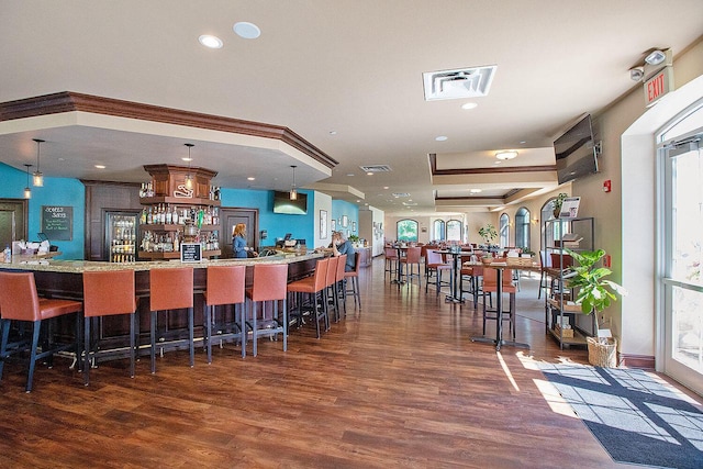 bar with pendant lighting, dark hardwood / wood-style flooring, and crown molding