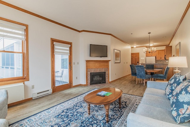 living room with light wood-type flooring, a wealth of natural light, a fireplace, and a baseboard radiator