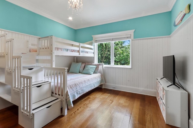 bedroom with hardwood / wood-style flooring, crown molding, and a chandelier