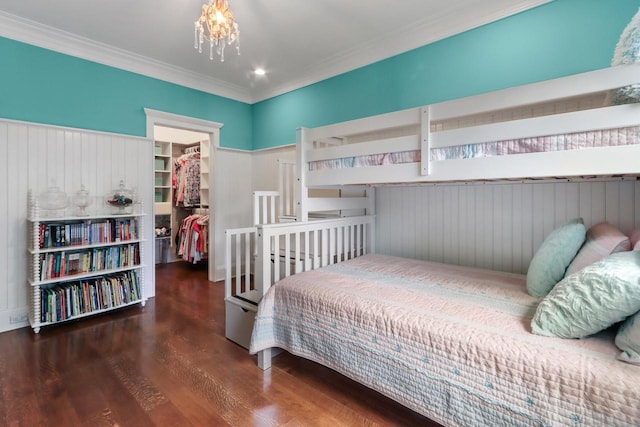 bedroom with a spacious closet, a closet, ornamental molding, and dark wood-type flooring