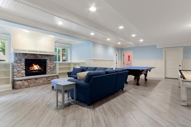 living room featuring a wealth of natural light, pool table, a stone fireplace, and light wood-type flooring