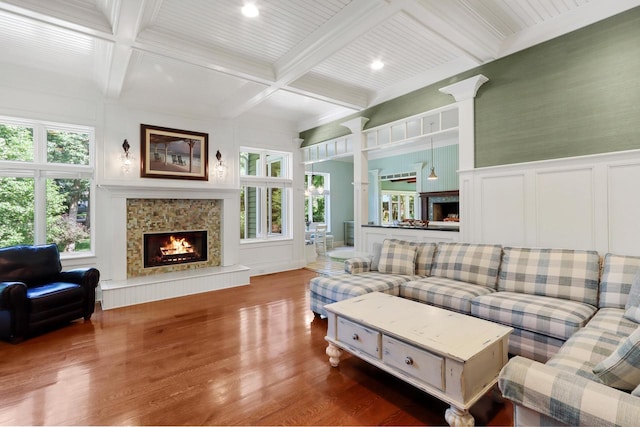 living room featuring a tiled fireplace, beamed ceiling, coffered ceiling, and wood-type flooring