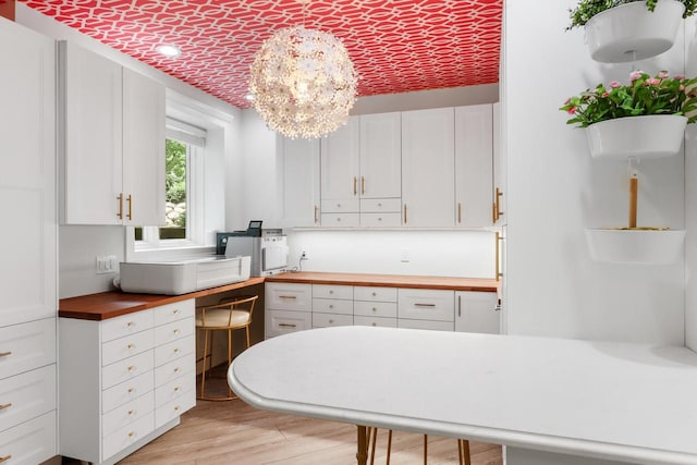 kitchen featuring an inviting chandelier, white cabinetry, light hardwood / wood-style flooring, and butcher block countertops