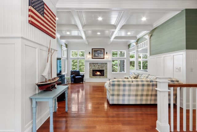 living room with a fireplace, beam ceiling, coffered ceiling, dark wood-type flooring, and ornamental molding