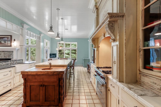 kitchen featuring wood counters, decorative light fixtures, sink, high end stove, and light tile patterned floors