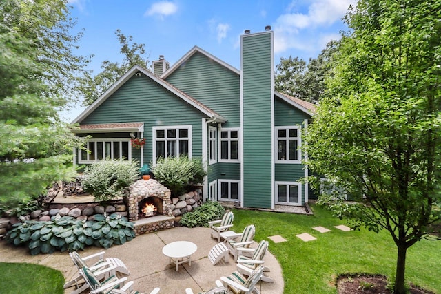 back of house featuring an outdoor stone fireplace, a lawn, and a patio