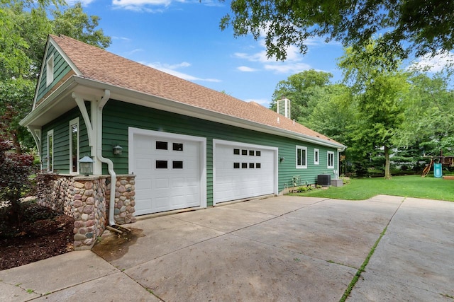 view of side of home featuring central air condition unit, a yard, and a garage