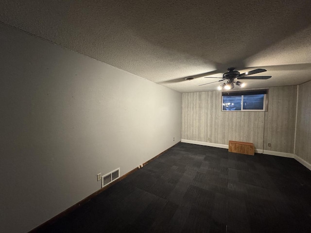 carpeted empty room featuring wooden walls and a textured ceiling