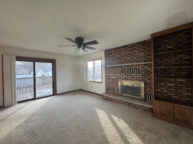 unfurnished living room featuring ceiling fan, a textured ceiling, carpet, and a brick fireplace