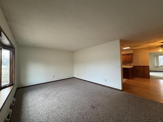 empty room featuring ceiling fan, light colored carpet, and a wealth of natural light