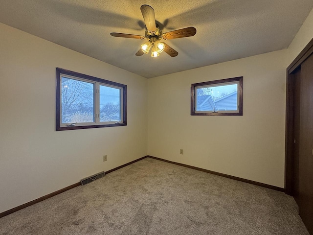 carpeted spare room with a textured ceiling and ceiling fan