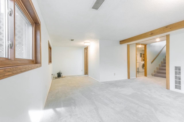 empty room featuring washer / dryer and light carpet