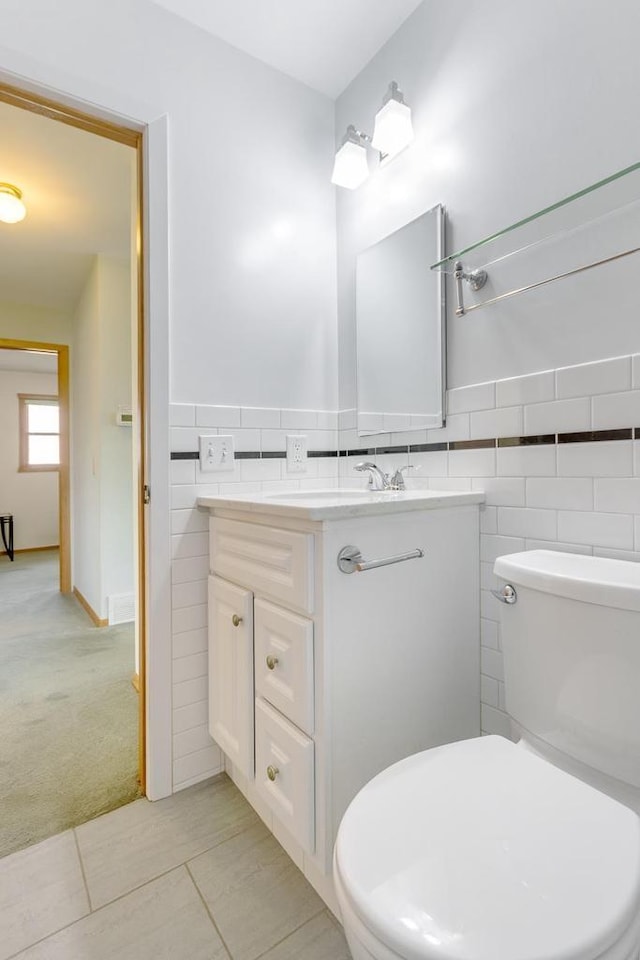 bathroom with vanity, toilet, and tile walls