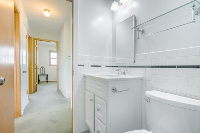 bathroom featuring vanity, tile walls, and toilet