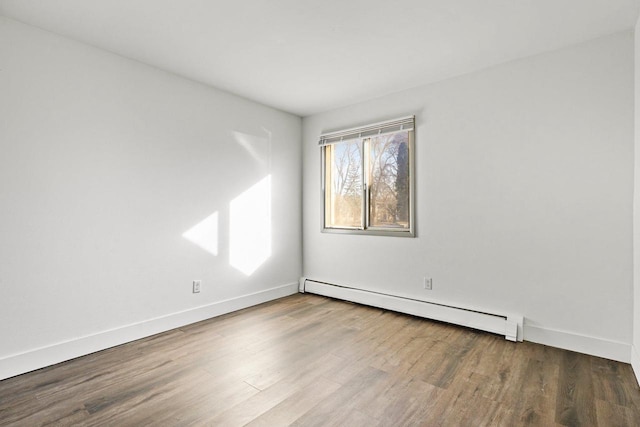 spare room featuring wood-type flooring and a baseboard radiator