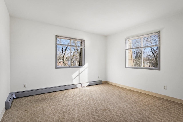 carpeted empty room featuring a baseboard heating unit and plenty of natural light