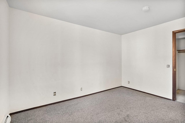 unfurnished room featuring a baseboard heating unit and carpet flooring