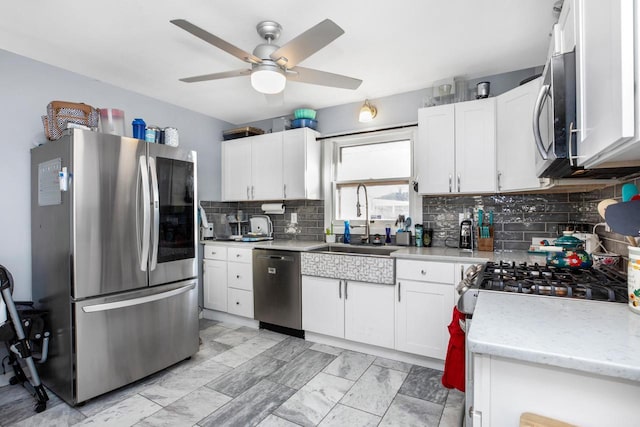 kitchen featuring sink, appliances with stainless steel finishes, ceiling fan, decorative backsplash, and white cabinets