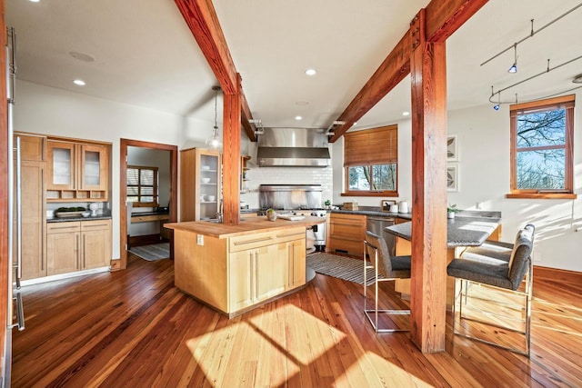 kitchen featuring dark wood-type flooring, light brown cabinetry, butcher block countertops, a center island, and wall chimney range hood