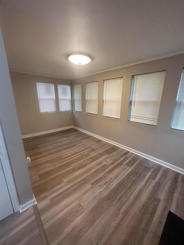 empty room with dark hardwood / wood-style flooring and crown molding