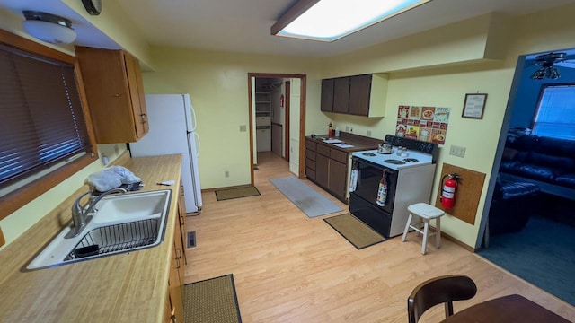 kitchen featuring white refrigerator, range with electric stovetop, light hardwood / wood-style floors, and sink