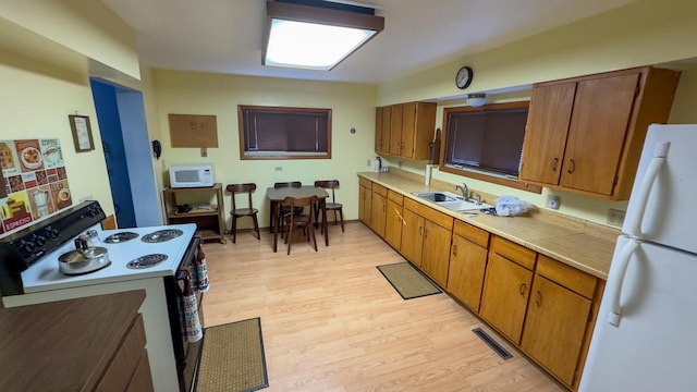 kitchen featuring sink, white appliances, and light wood-type flooring