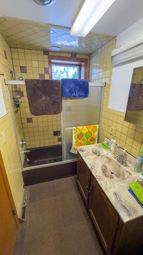 bathroom featuring tile walls, tiled shower / bath combo, and vanity