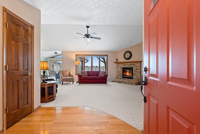 carpeted entryway with ceiling fan, a textured ceiling, and a fireplace