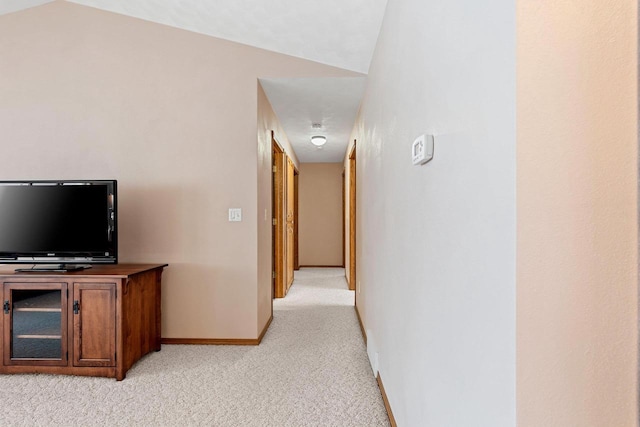 hall featuring lofted ceiling and light colored carpet