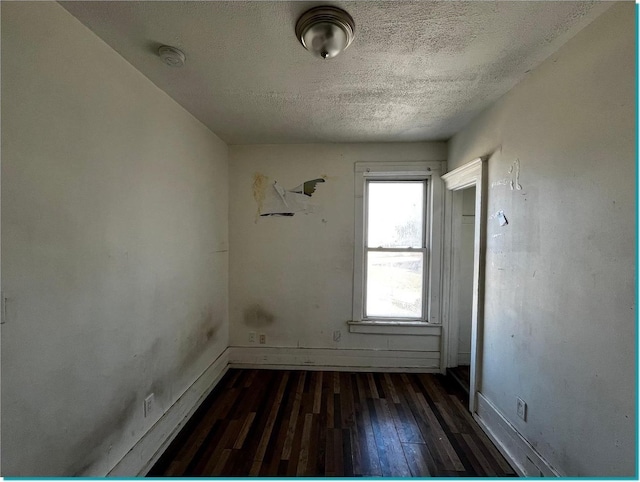 spare room with a textured ceiling and dark hardwood / wood-style floors