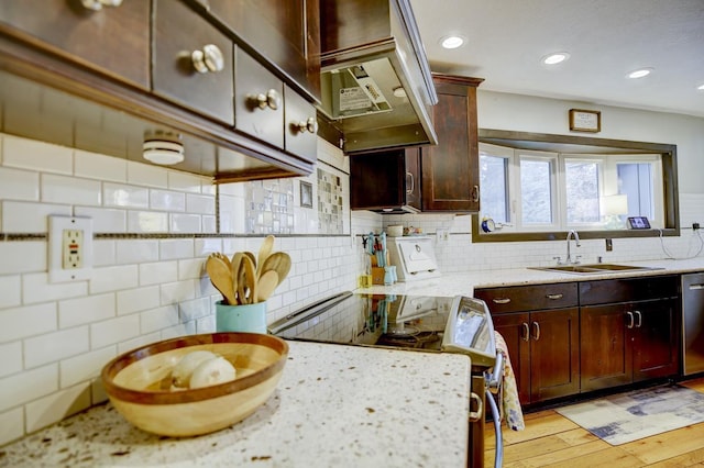 kitchen featuring light hardwood / wood-style floors, appliances with stainless steel finishes, decorative backsplash, light stone countertops, and sink